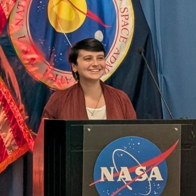 Yasemin Gokcen speaking at a NASA podium